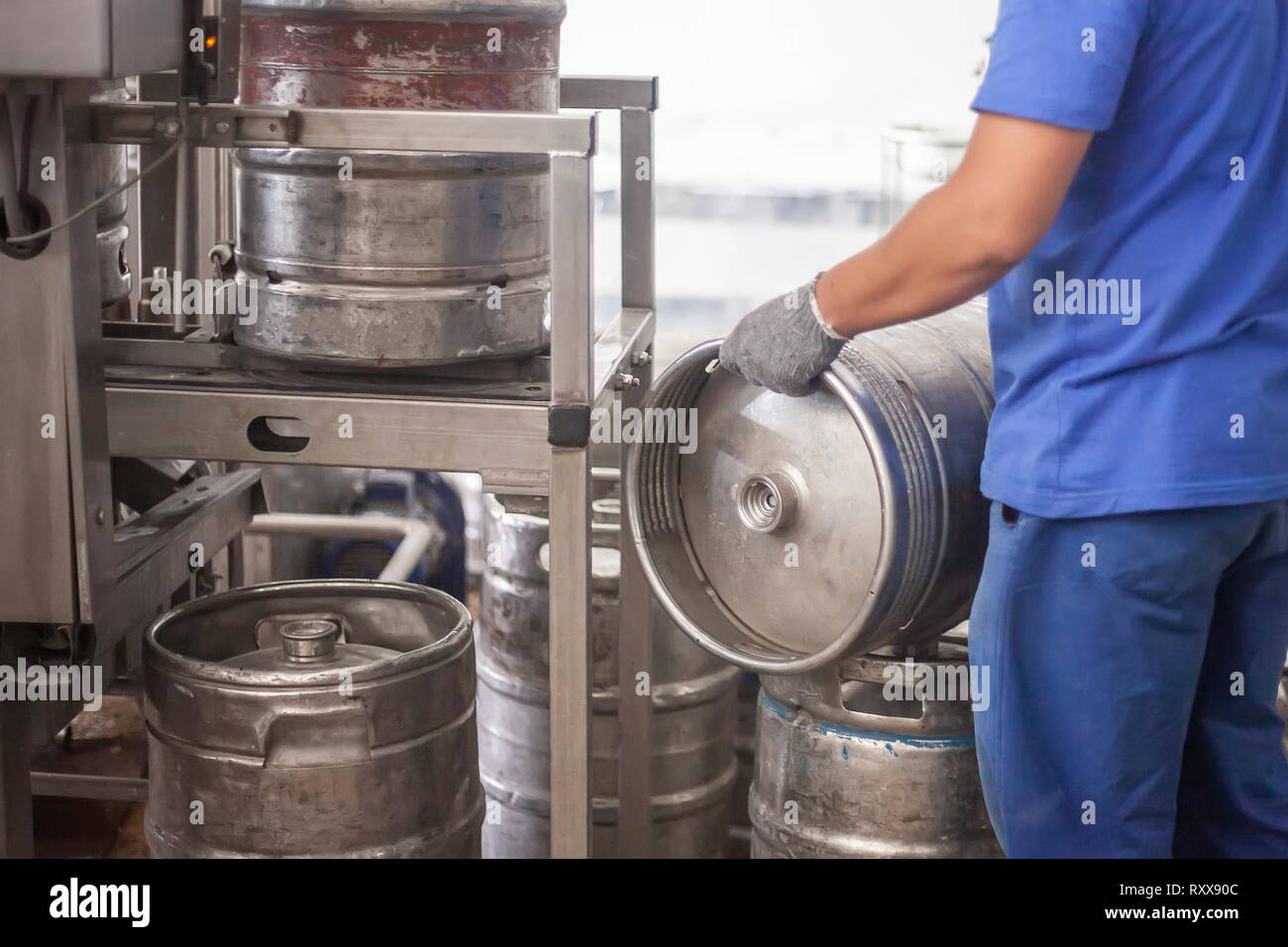 Uomo con acciaio barili di birra sulla linea di produzione in fabbrica Foto Stock