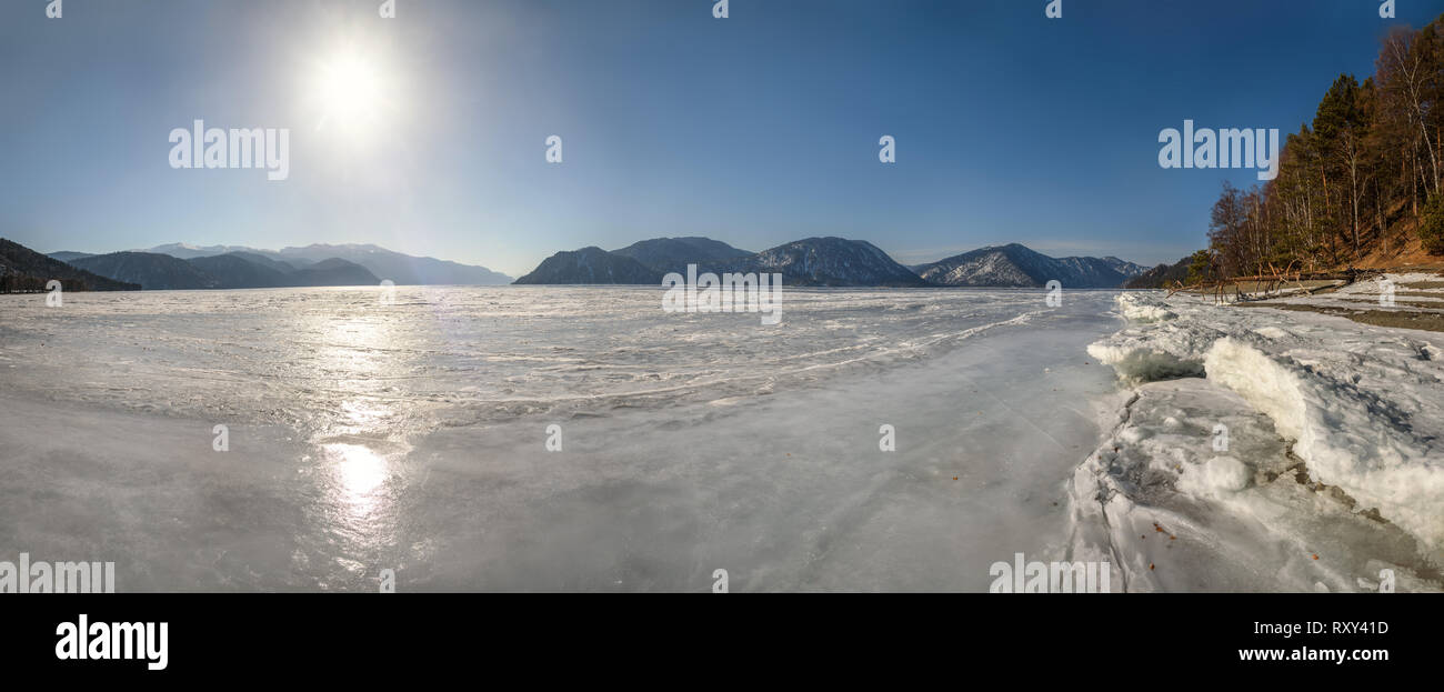 Il bellissimo panorama di congelati Lago Teletskoye con ghiaccio, montagne, sun e pino che giace sulla riva in una giornata di sole Foto Stock