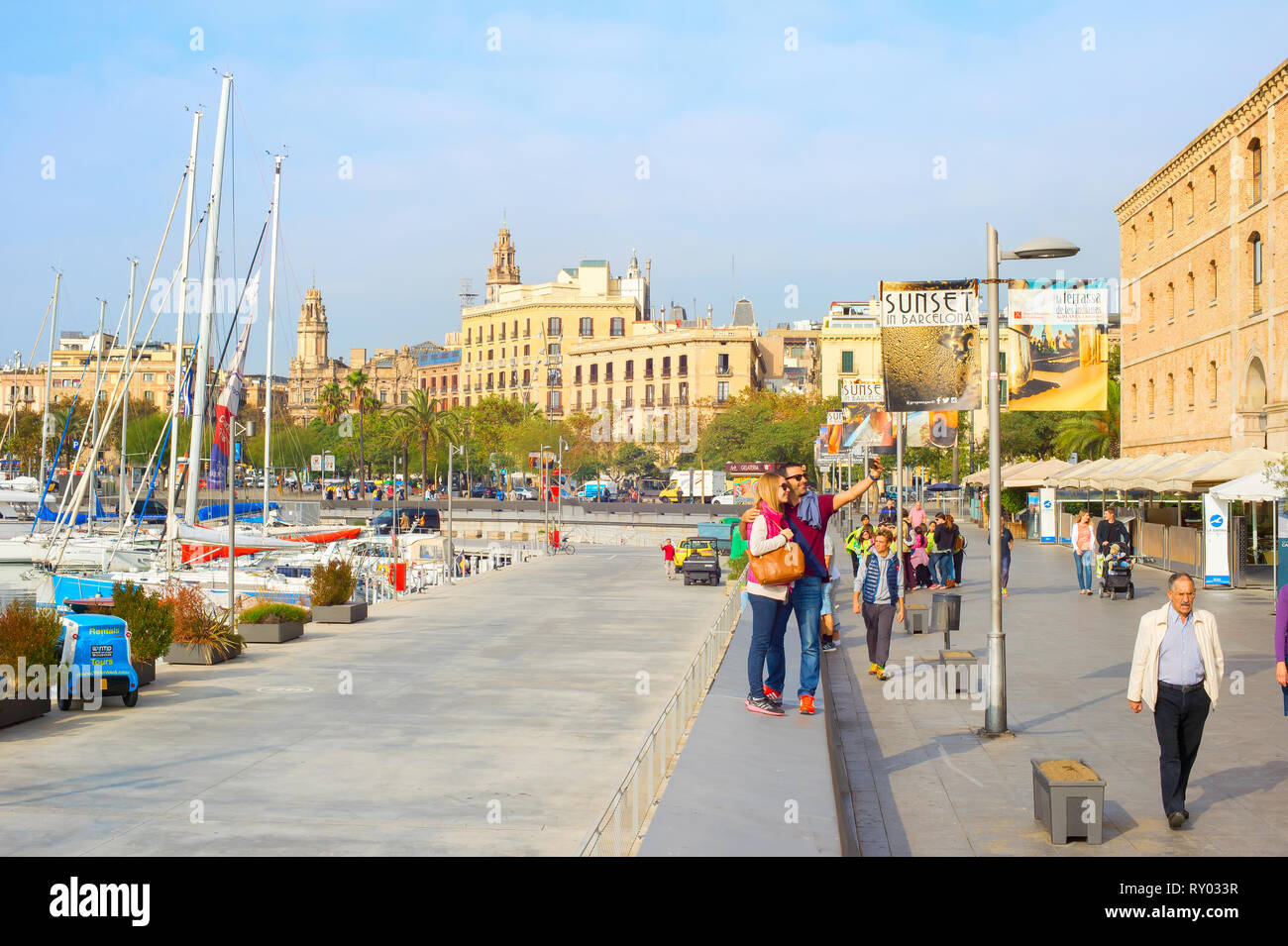 Barcellona, Spagna - 3 Novembre 2016: giovane tenendo selfie con lo smartphone sul terrapieno di Barcellona dalla marina con barche in sera la luce solare, Spagna Foto Stock