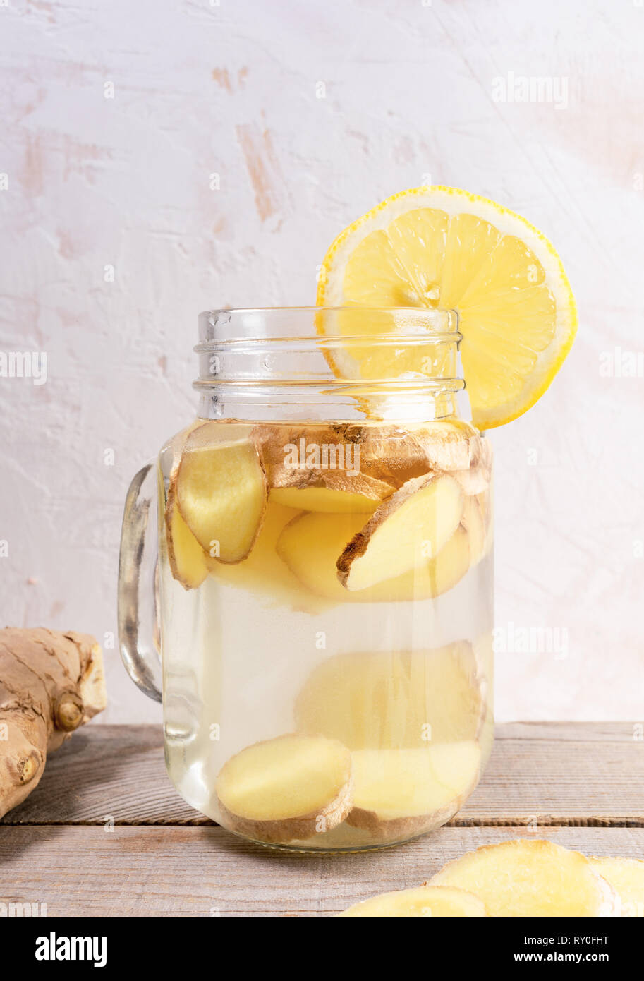 Close-up il vasetto di vetro con acqua di zenzero e la fetta di limone su un tavolo di legno. Foto Stock