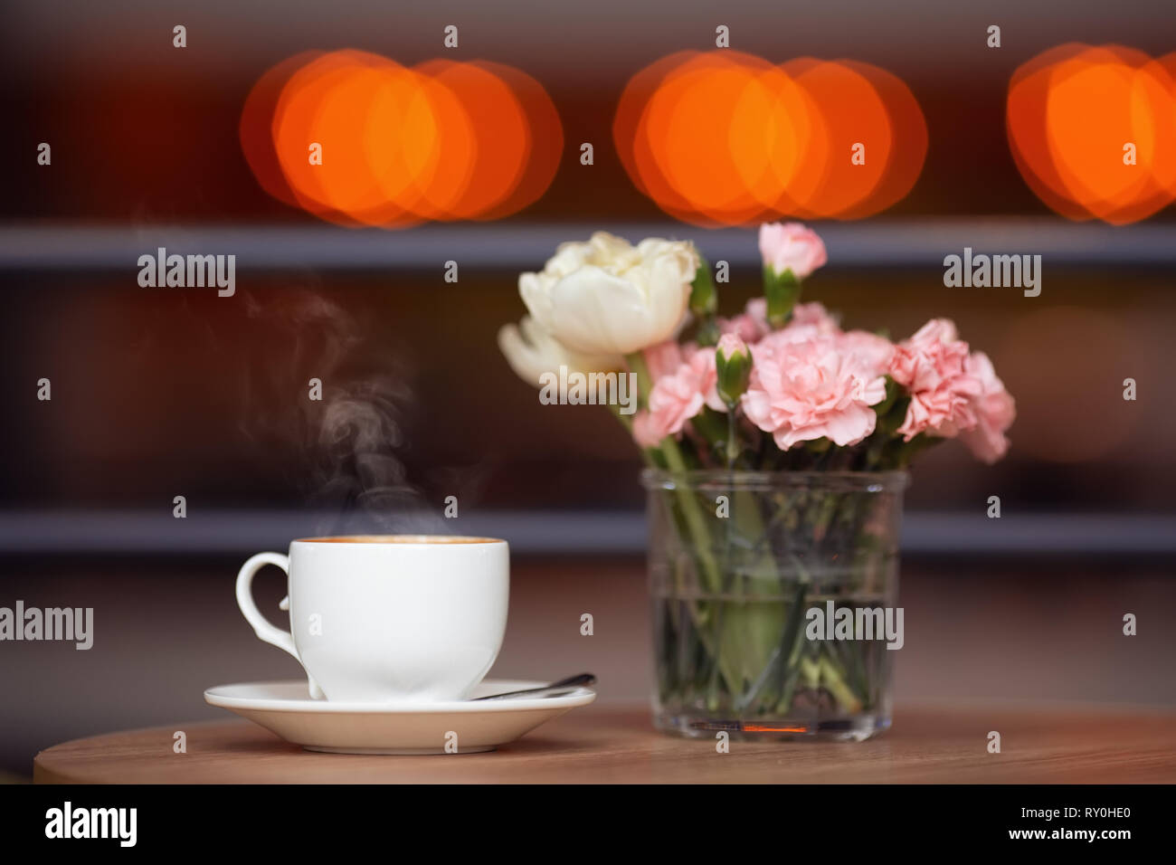 White tazza di caffè e fiori freschi sul tavolo in cafe Foto Stock