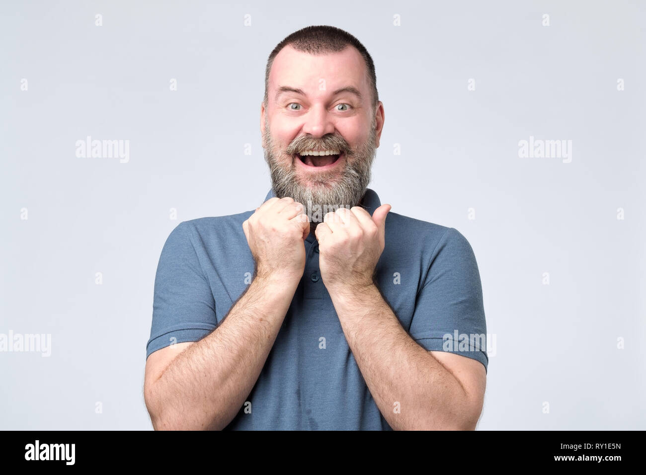 Eccitato uomo barbuto in piedi con i pugni fino Foto Stock