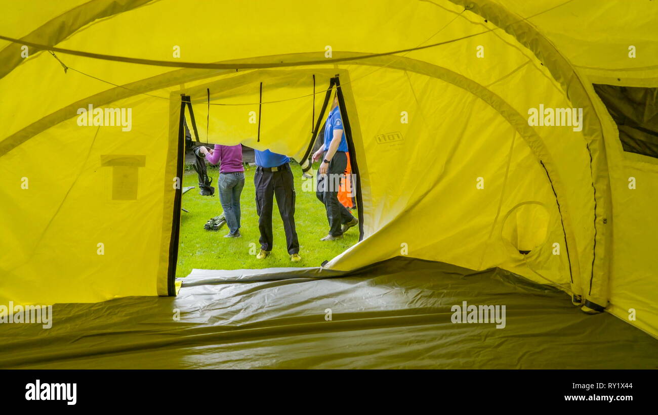 Sguardo interno della grande tenda gialla in cui le persone sono la piegatura della parte sportello della tenda Foto Stock