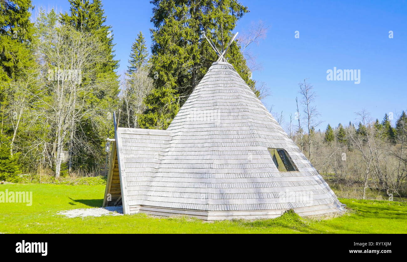 La forma triangolare casa in legno con alti pini sul retro in una giornata di sole Foto Stock