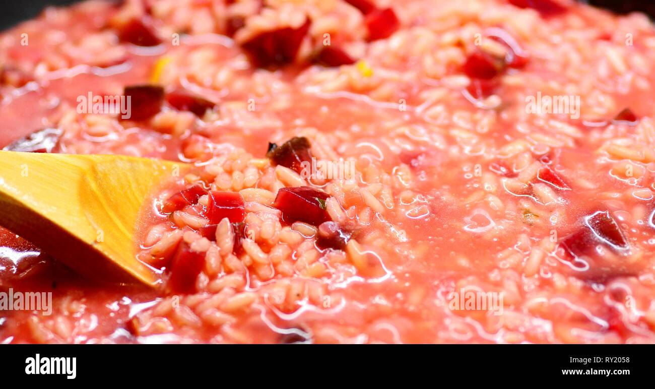 Close-up di un Italiano cremoso Risotto di barbabietole e agitando il cucchiaio di legno. Foto Stock