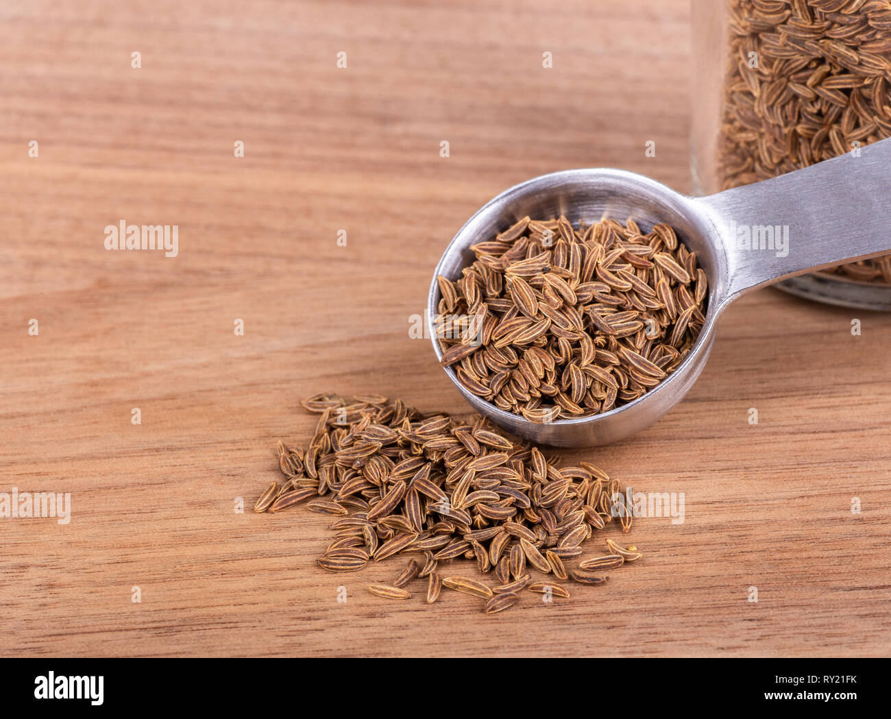 Primo piano di semi di cumino e il misurino su una tavola di legno con spazio di copia Foto Stock