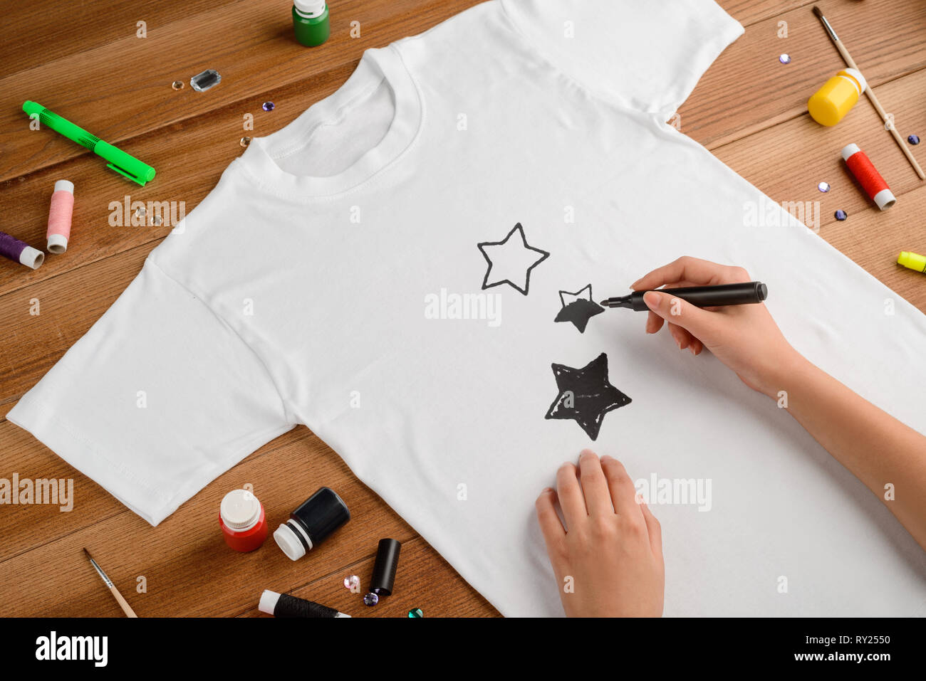 Donna disegno stelle sulla t-shirt Foto Stock