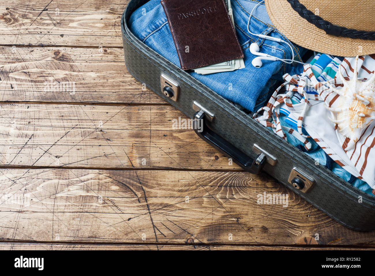 Preparazioni per il viaggio concetto con la valigia, vestiti e accessori su un vecchio tavolo di legno. Vista dall'alto uno spazio di copia, Foto Stock