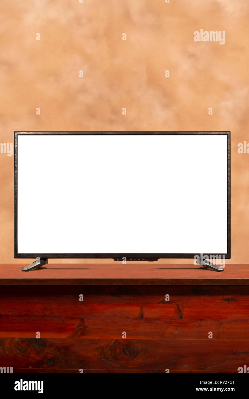 Colpo verticale di un fustellato a grande schermo tv con copia spazio sul tavolo. Brown confuso sfondo. Foto Stock