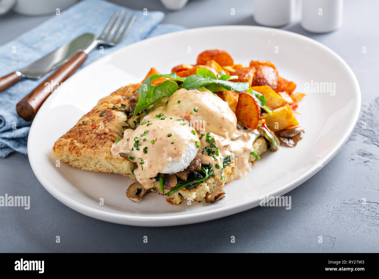 Uova Benedict con focaccia e patate Foto Stock