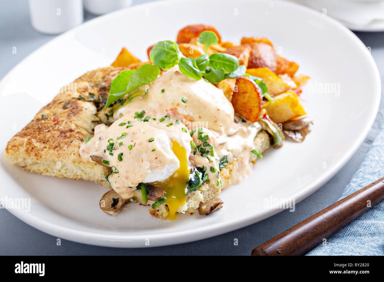 Uova Benedict con focaccia e patate Foto Stock