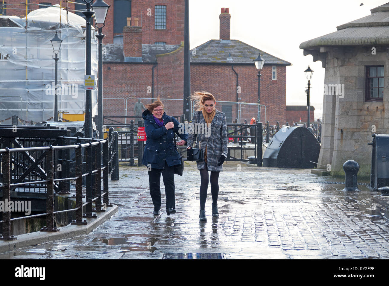 Una donna di mezza età e una donna nel suo 20's fuori camminato su un molto ventoso giorno in Liverpool Regno Unito. Foto Stock