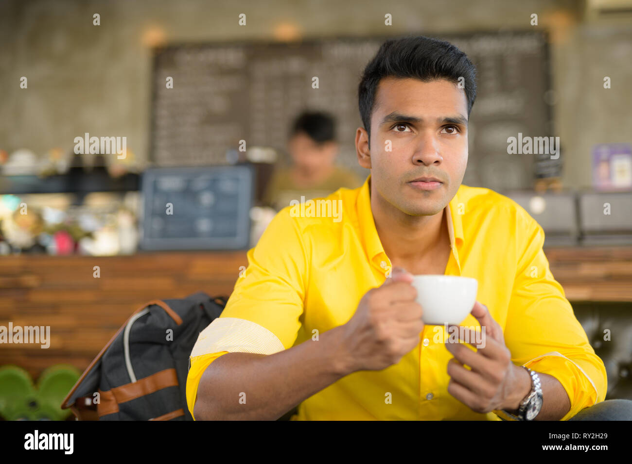 Bel giovane uomo indiano di bere il caffè presso la caffetteria Foto Stock