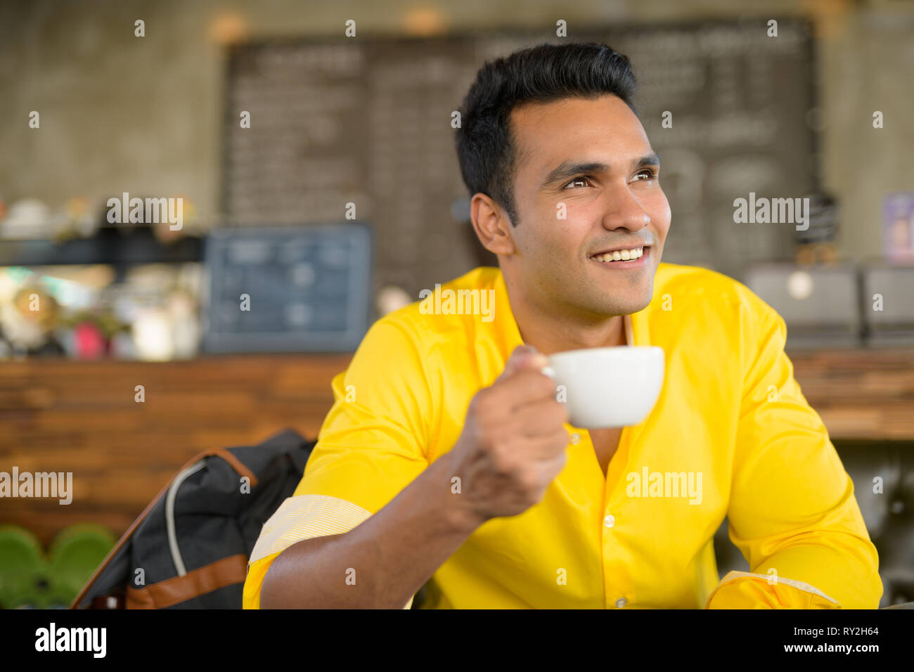 Giovani indiani felice l'uomo di pensiero e di seduta al coffee shop Foto Stock