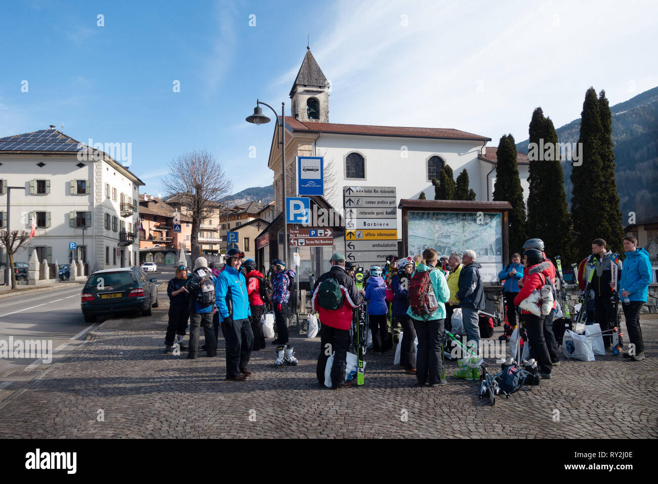 Gli sciatori in attesa ad una fermata dello ski bus, Pinzolo village, Dolomiti di Brenta, Italia del nord Europa Foto Stock