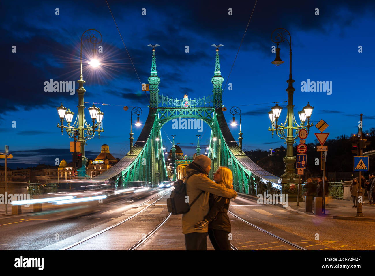 9097 Una giovane coppia sul ponte della Libertà illuminata di notte con il Gellert Hotel in background, Budapest, Ungheria Foto Stock