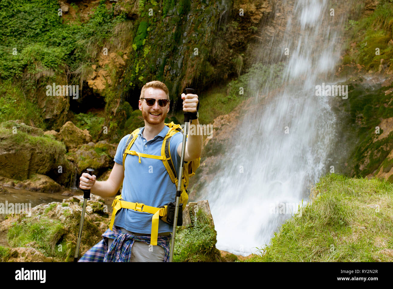 Bel giovane escursionista fermato accanto a una cascata di montagna di prendere un periodo di riposo Foto Stock