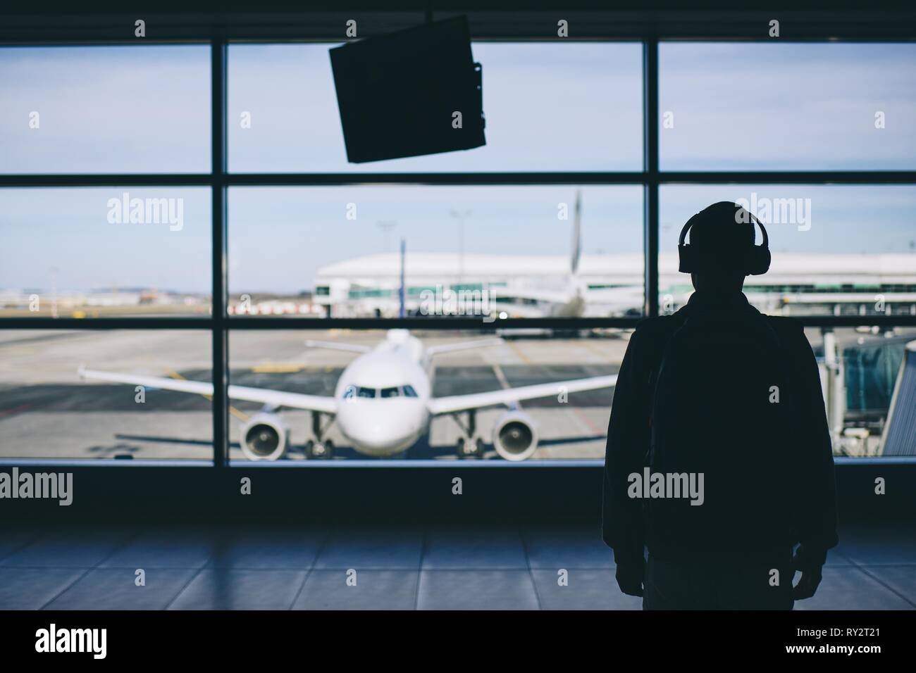 Passeggeri con le cuffie. Giovane uomo che cammina attraverso il terminal aeroportuale per aereo. Foto Stock