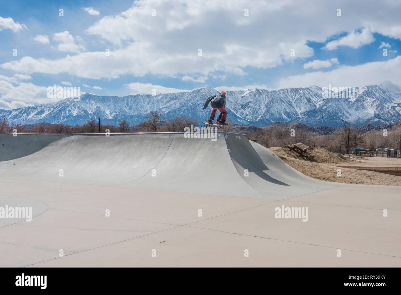 Giovane guidatore di skateboard facendo trucchi a skate park di Lone Pine, California. Foto Stock