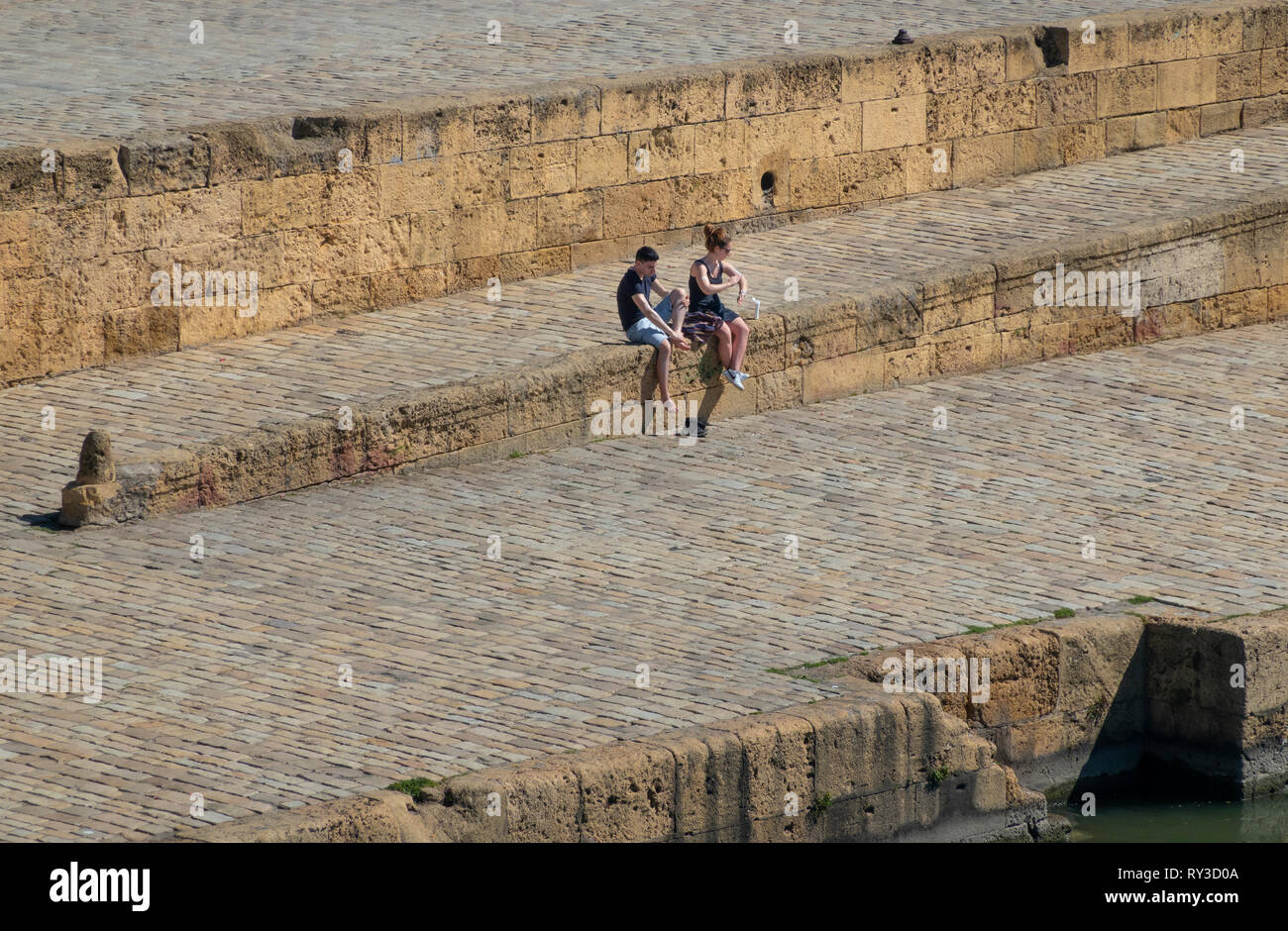 Una giovane coppia applying​ lozione protettiva per il sole vicino al fiume Guadalquivir a Siviglia Foto Stock