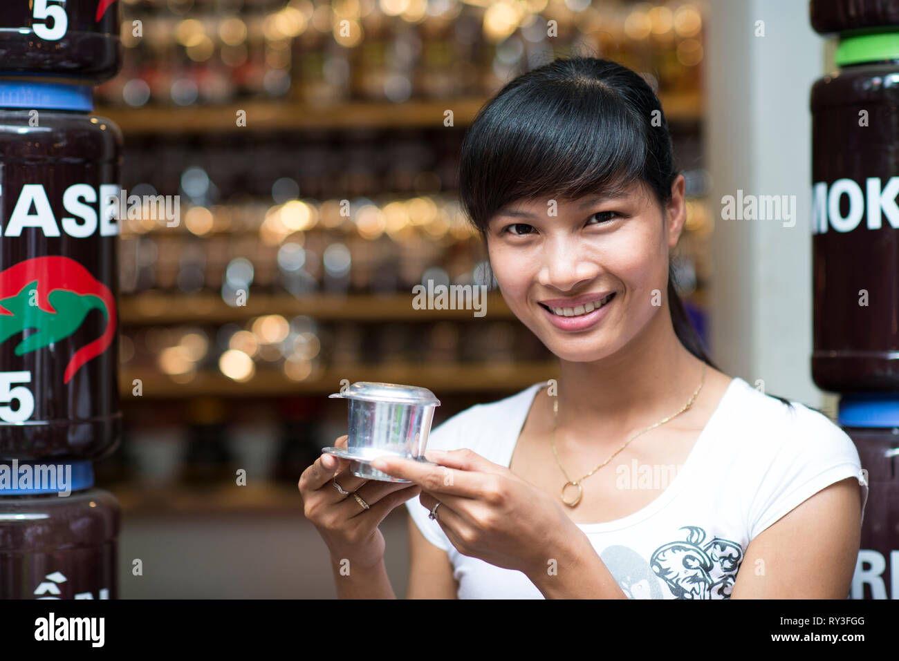 Una donna asiatica sorridente con un caffè vietnamita - latte caldo il caffè con il latte condensato in Vietnam stile. Tradizionale bevanda vietnamita Foto Stock