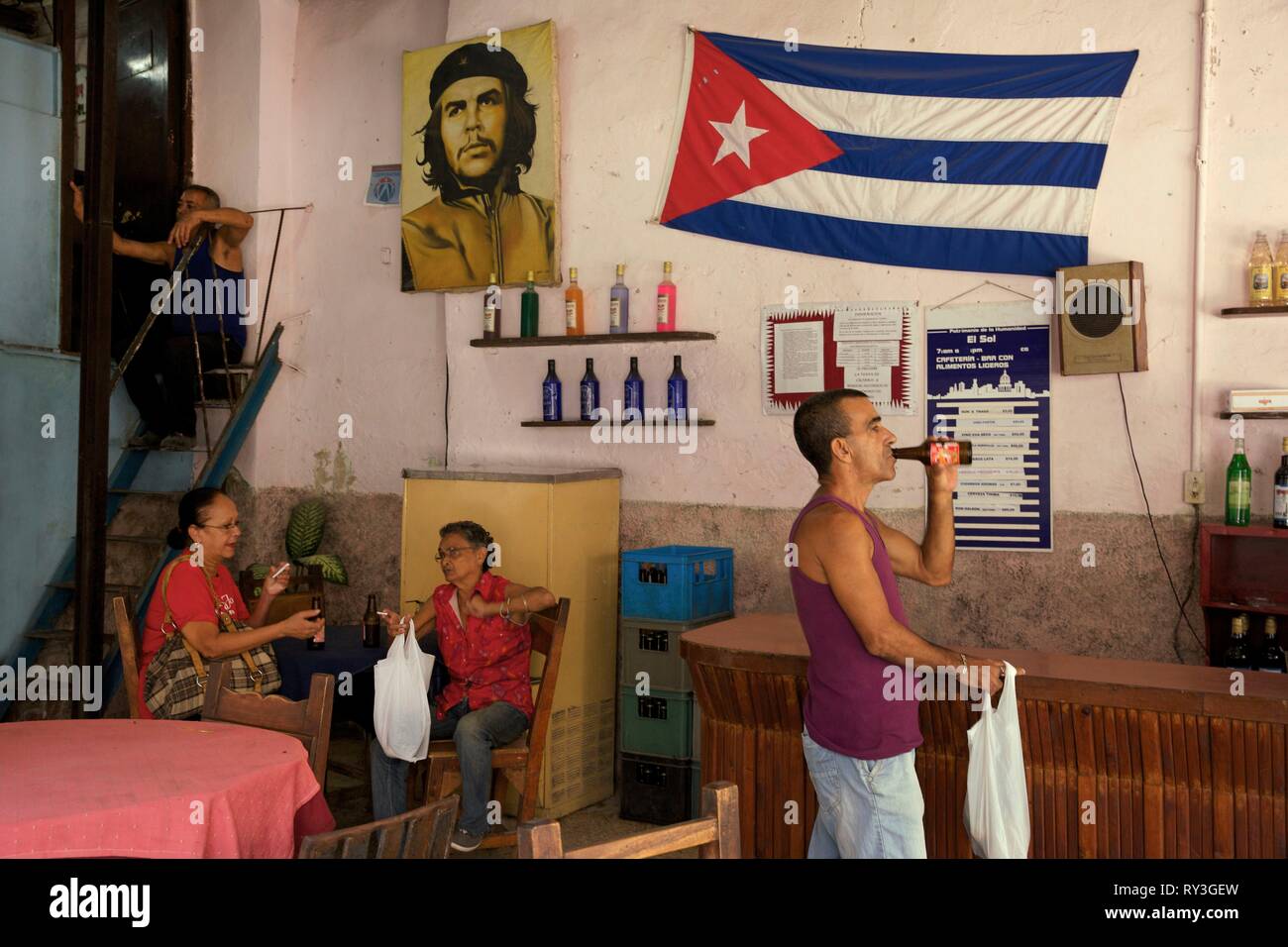 Cuba, La Habana, Havana vecchia, classificato come patrimonio mondiale dall UNESCO, uomo di bere una birra e donne anziane seduto in una barra di stato decorato con una bandiera cubana e un ritratto di Che Guevara Foto Stock