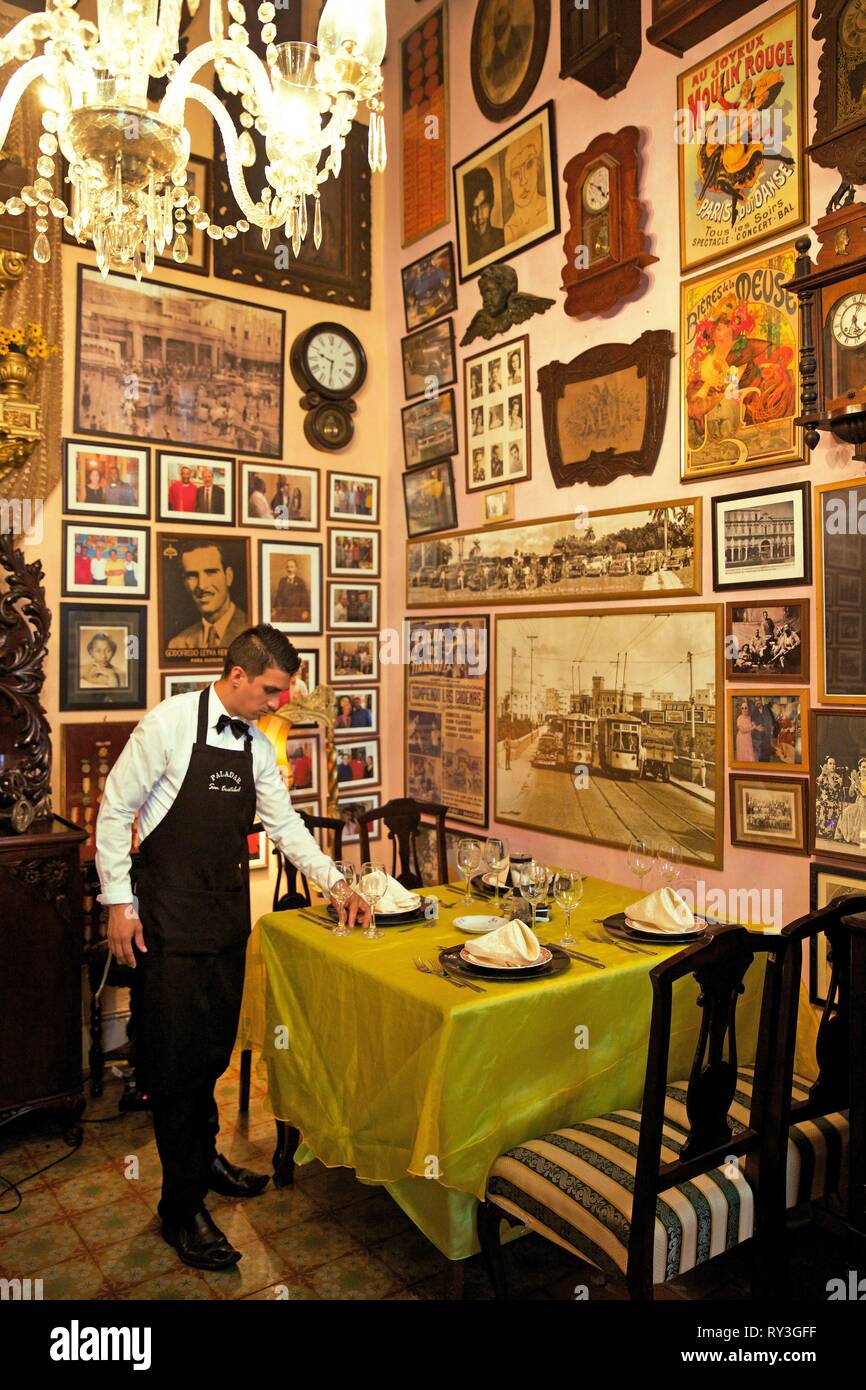 Cuba, La Habana, Centro Habana, il vecchio server in una stanza piena di vecchie foto del paladar San Cristobal, uno di La Havana più famosi ristoranti privati Foto Stock