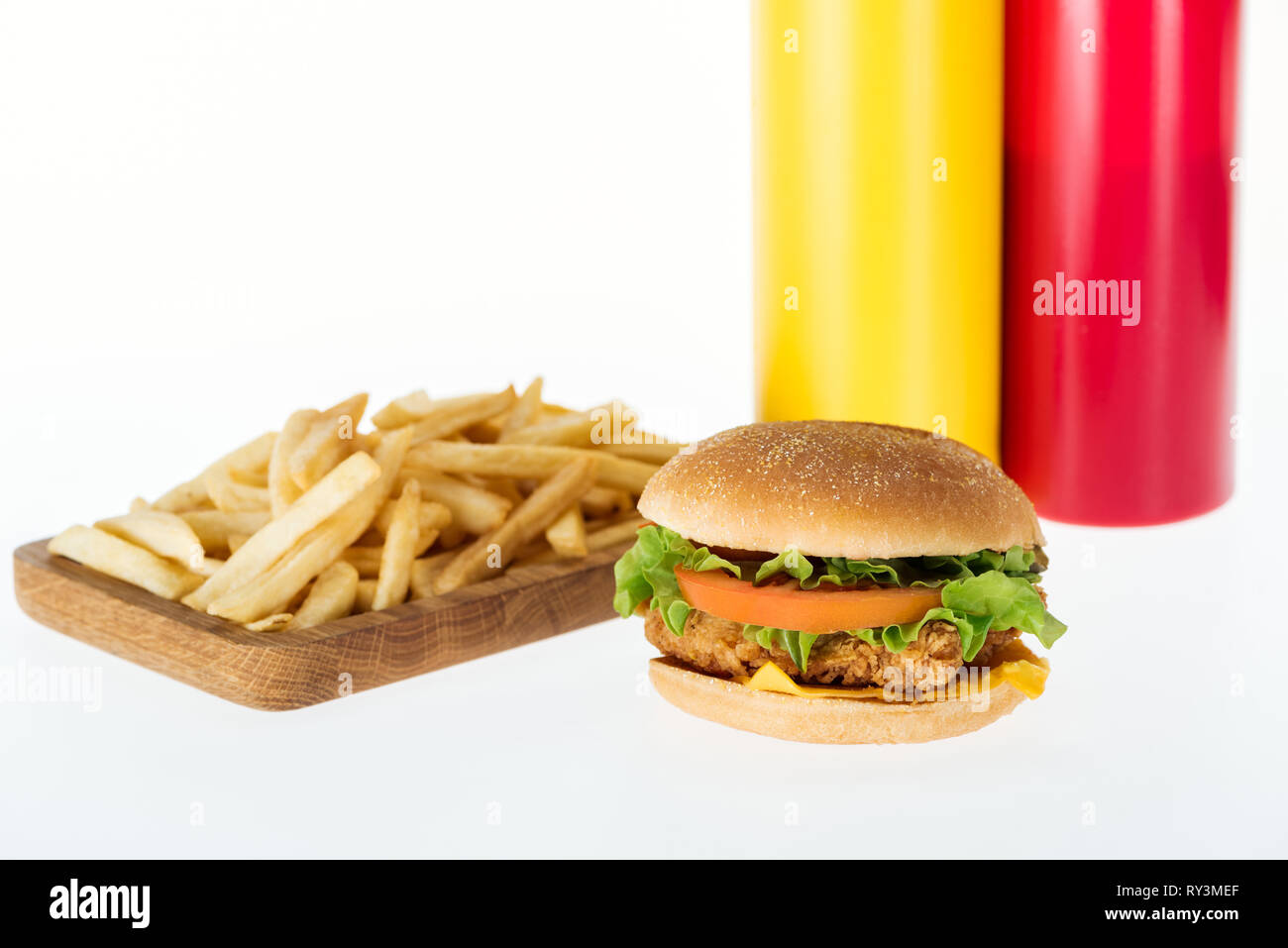 Gustoso pollo Burger vicino a patatine fritte e bottiglie isolato su bianco Foto Stock