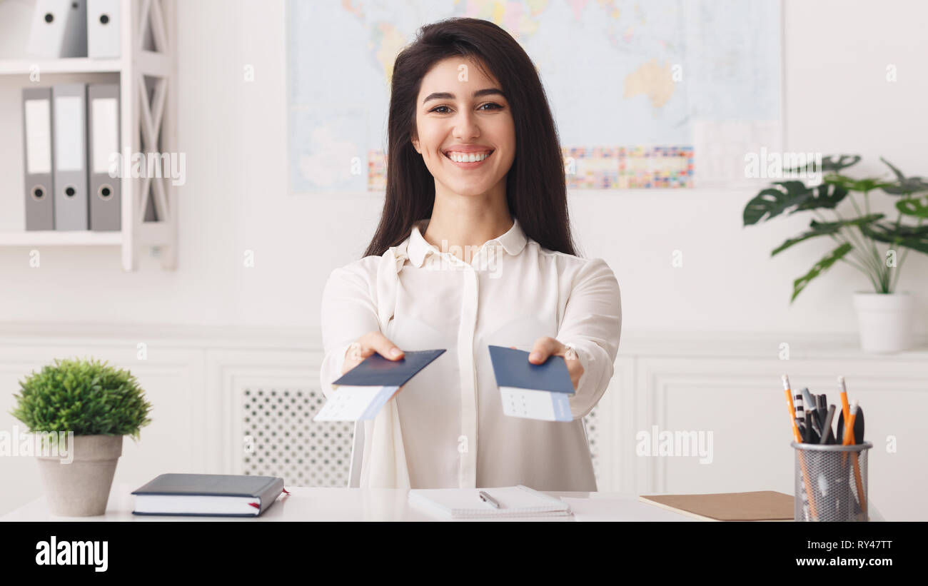Felice travel agent si allunga i passaporti con biglietti Foto Stock