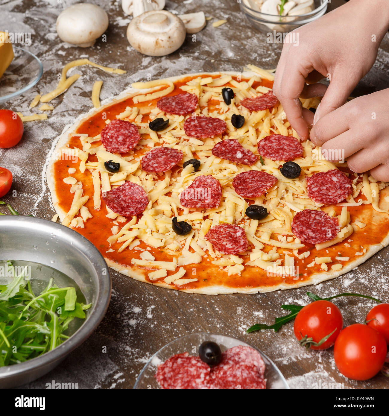Donna decorare la pizza con vari ingredienti, il raccolto Foto Stock