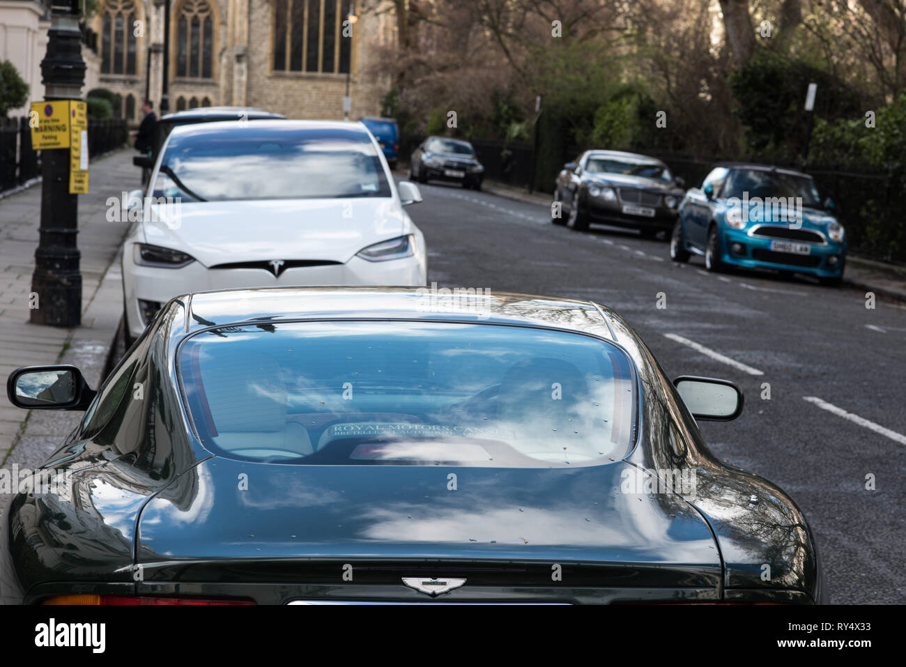 Belgravia, London, Regno Unito - Marzo 2019 - Aston Martin e la Tesla elettrico auto parcheggiate accanto a ogni altro a Londra Foto Stock