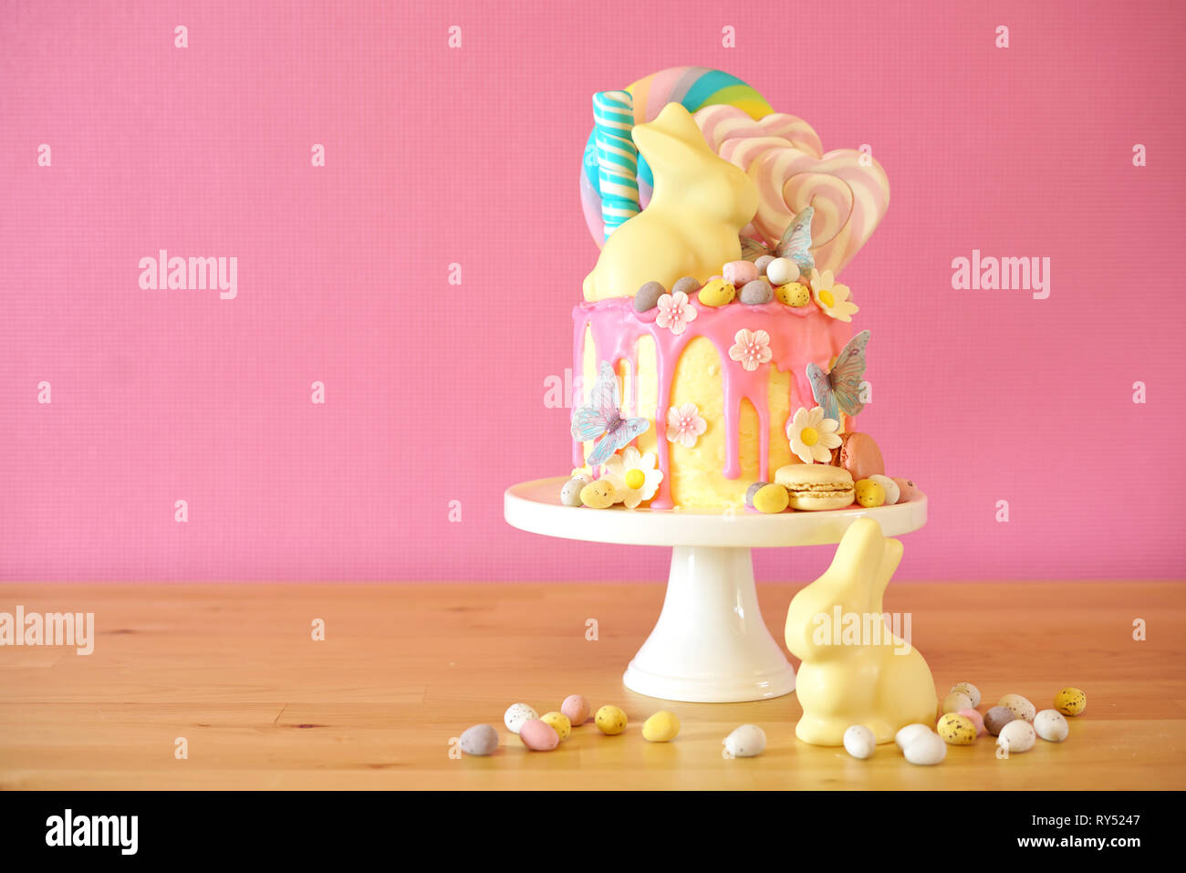Sulla tendenza di Pasqua tema candy land gocciolare torta decorata con connettori lollipop, candy uova e cioccolato bianco bunny in parte messa in tavola. Foto Stock