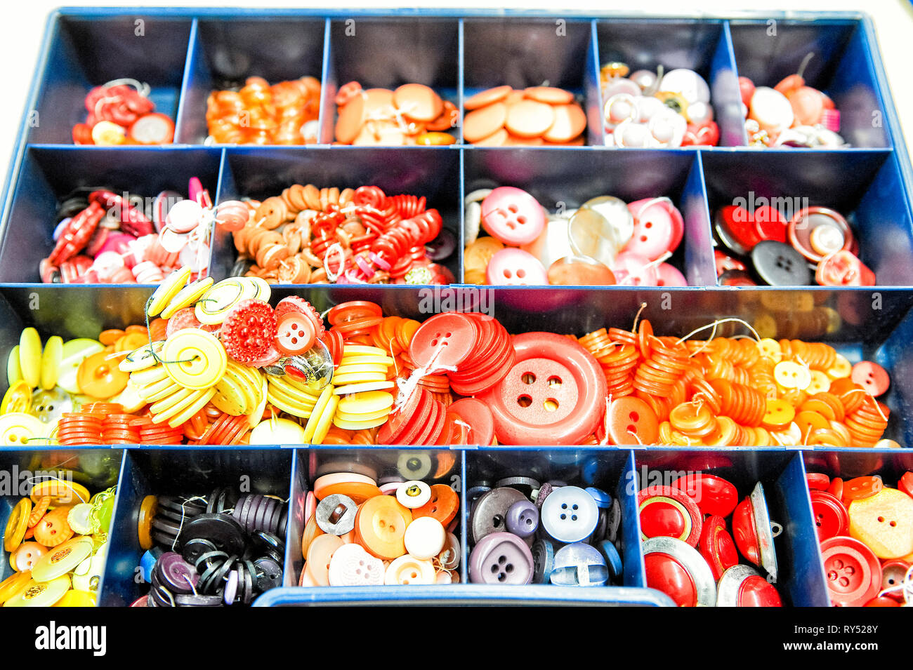 Ein Sortierkasten mit unterschiedlichen Knoepfen nach Farben sortiert. Foto Stock