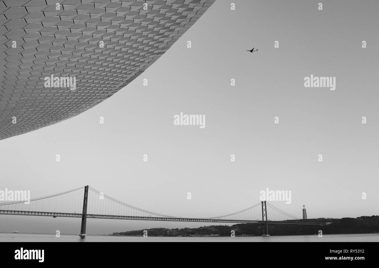 Airplaine arrivando a Lisbona con il 25 di aprile del ponte in background al tramonto. Lisbona portogallo Foto Stock