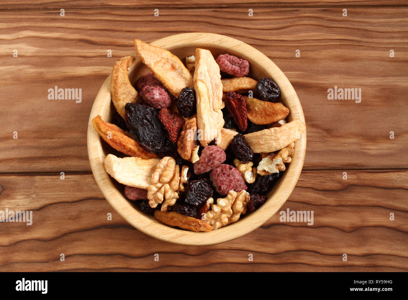 Mix di frutta secca pezzi di mela e pera, secche Prugne blu, fragole, lamponi e ciliegie e noci in una ciotola di bambù su un tavolo di legno. Foto Stock