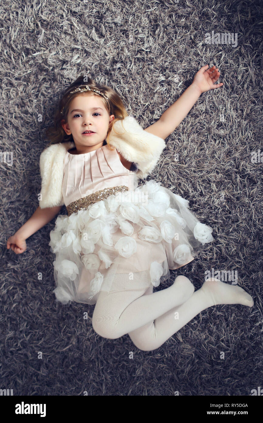 Bambina con bel vestito sdraiato sul pavimento Foto Stock