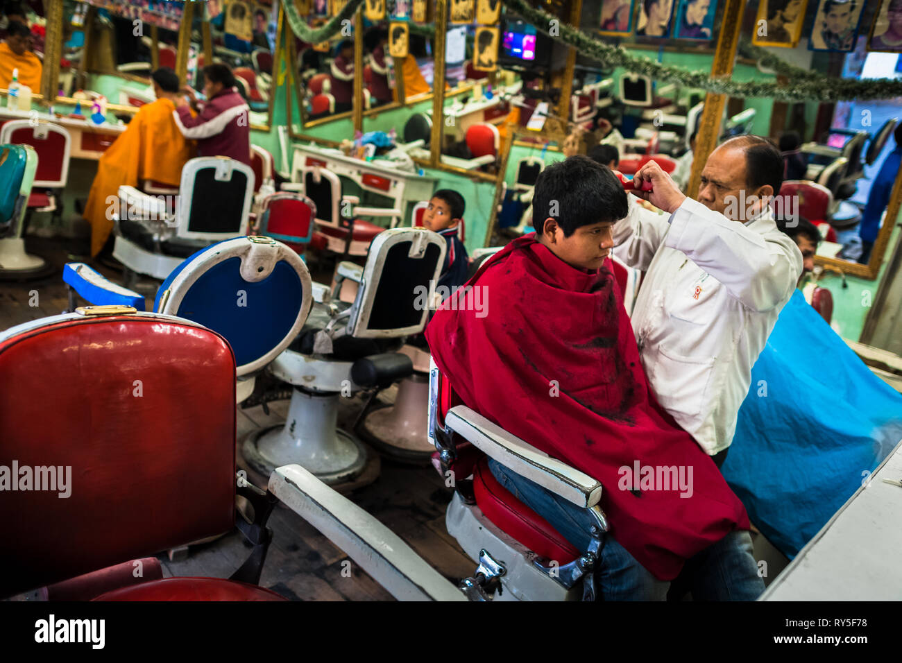 Un peruviano parrucchiere taglia un ragazzi i capelli in un vintage Barber shop a Cuzco, Perù. Foto Stock