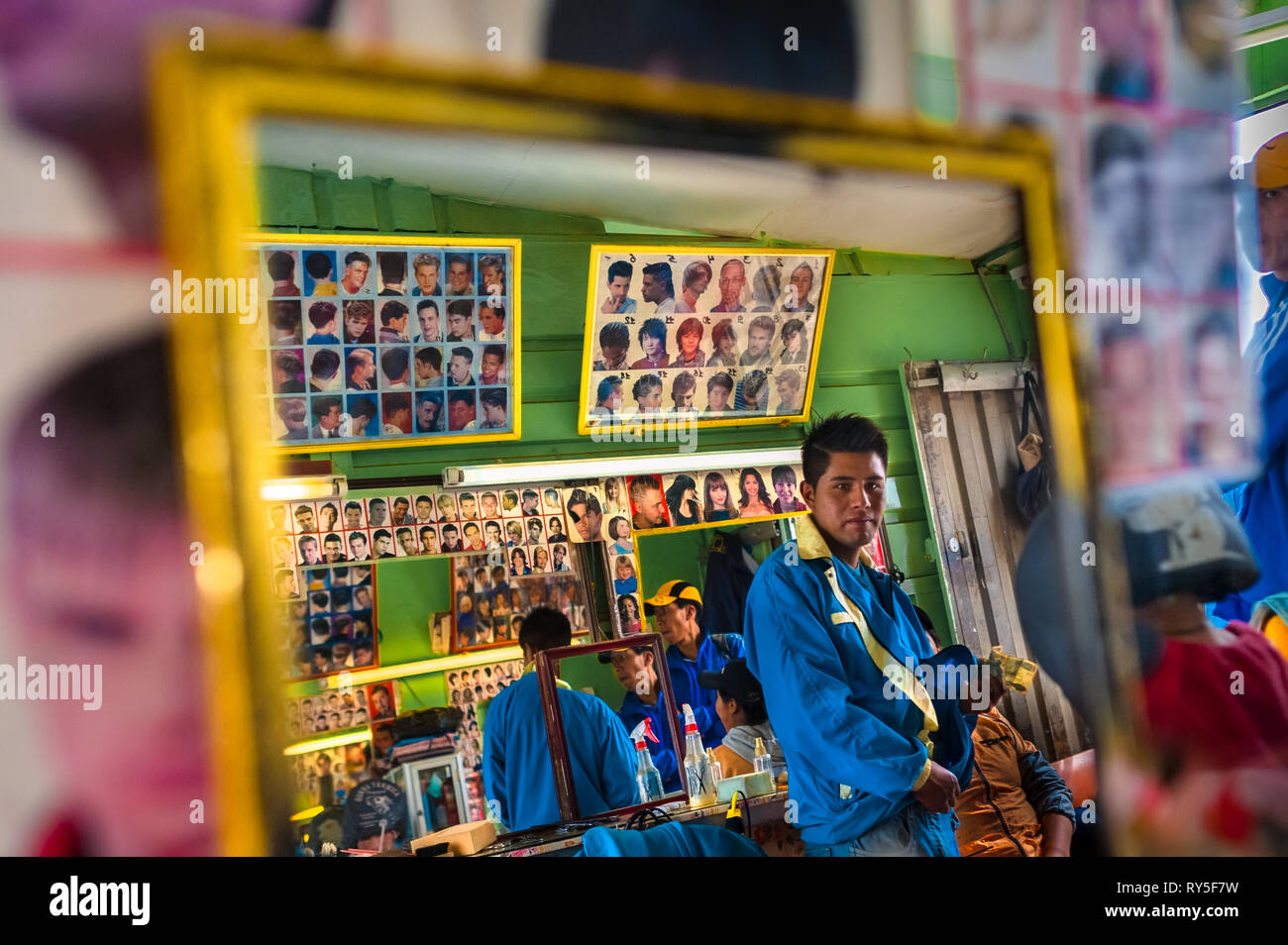 Un giovane parrucchiere boliviano le tasse del suo cliente per un taglio di capelli in un negozio di barbiere di El Alto in Bolivia. Foto Stock