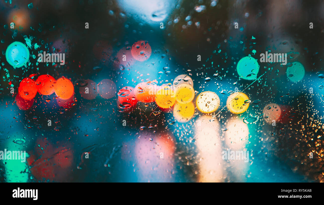 Gocce di acqua di pioggia nella notte o sera le luci di strada sul vetro azzurro sfondo. Street Bokeh Lights Out di messa a fuoco. Autunno sfondo astratto Foto Stock
