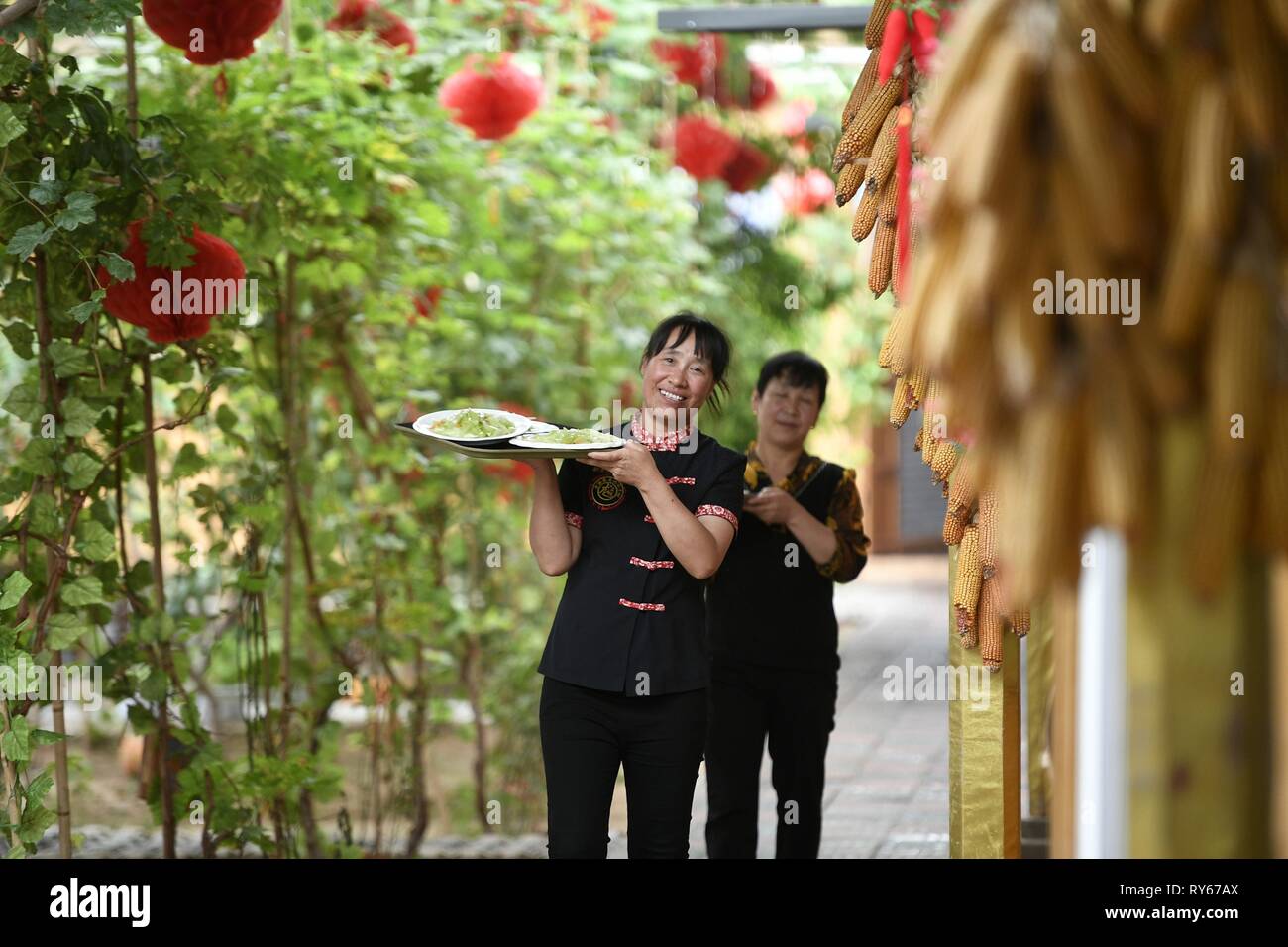 (190312) -- Pechino, 12 marzo 2019 (Xinhua) -- i membri dello staff servono piatti in un ristorante Longwangba villaggio di Xiji nella contea di Guyuan, a nord-ovest della Cina di Ningxia Hui Regione autonoma, il 30 agosto 2018. (Xinhua/Wang Peng) Foto Stock