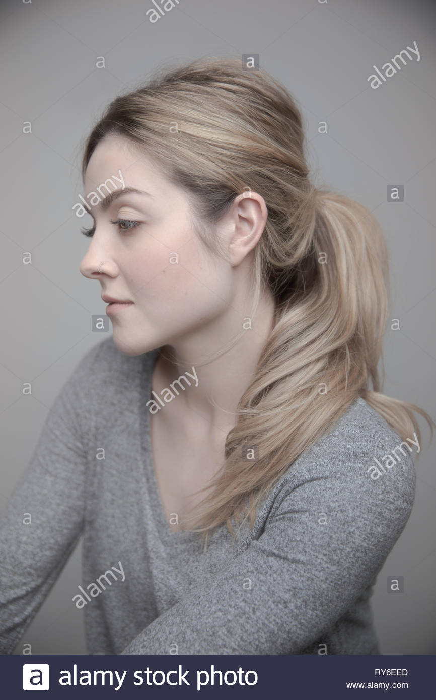 Ritratto riflessivo bella giovane donna con capelli biondi e naso anello Foto Stock
