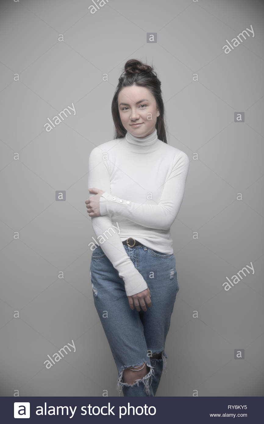 Ritratto fiducioso giovane e bella bruna donna in jeans strappati e turtleneck maglione Foto Stock