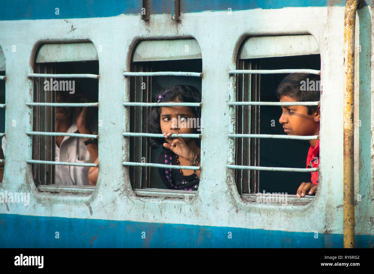 Preoccupato ragazza e bambini dietro le barre di finestra su India treno ferroviario, Delhi Foto Stock