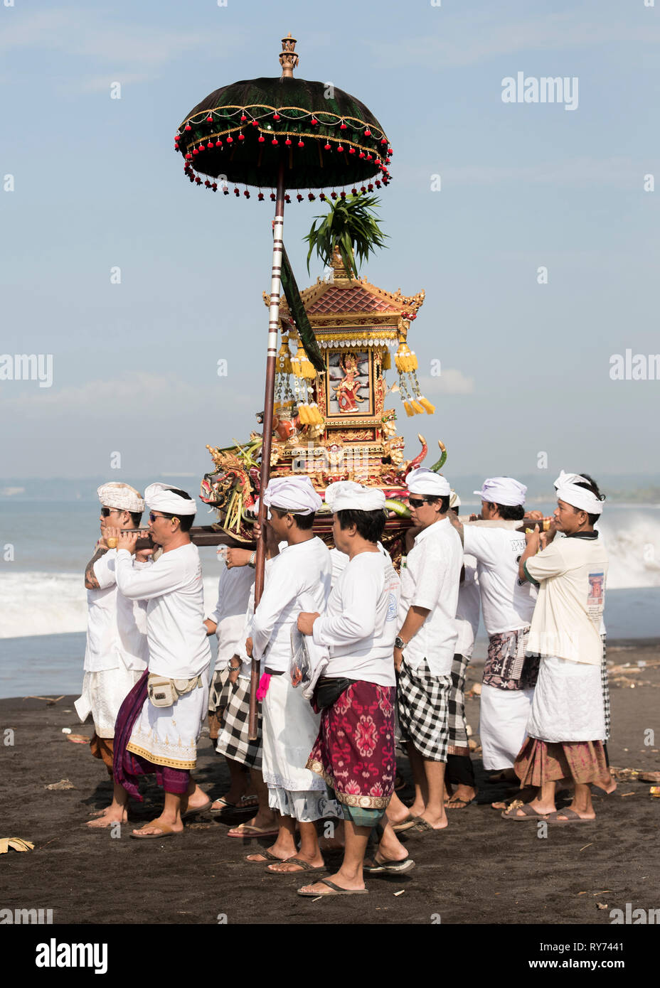 Gli uomini in abiti tradizionali che trasportano palanquin mentre passeggiate in spiaggia contro il cielo durante la giornata di sole Foto Stock