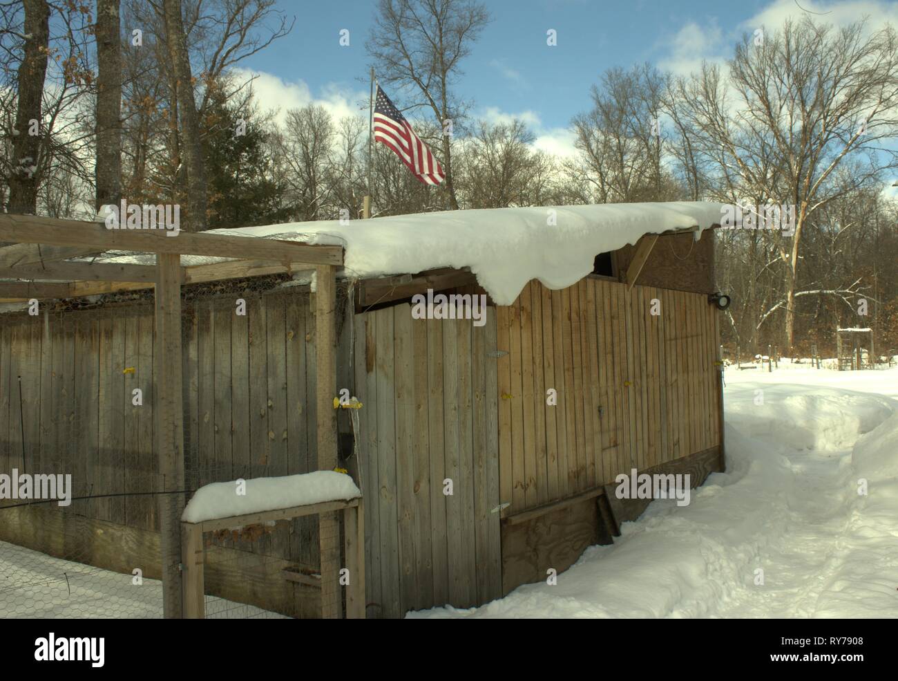 La neve di sgocciolamento un capannone di legno su una giornata invernale e Foto Stock