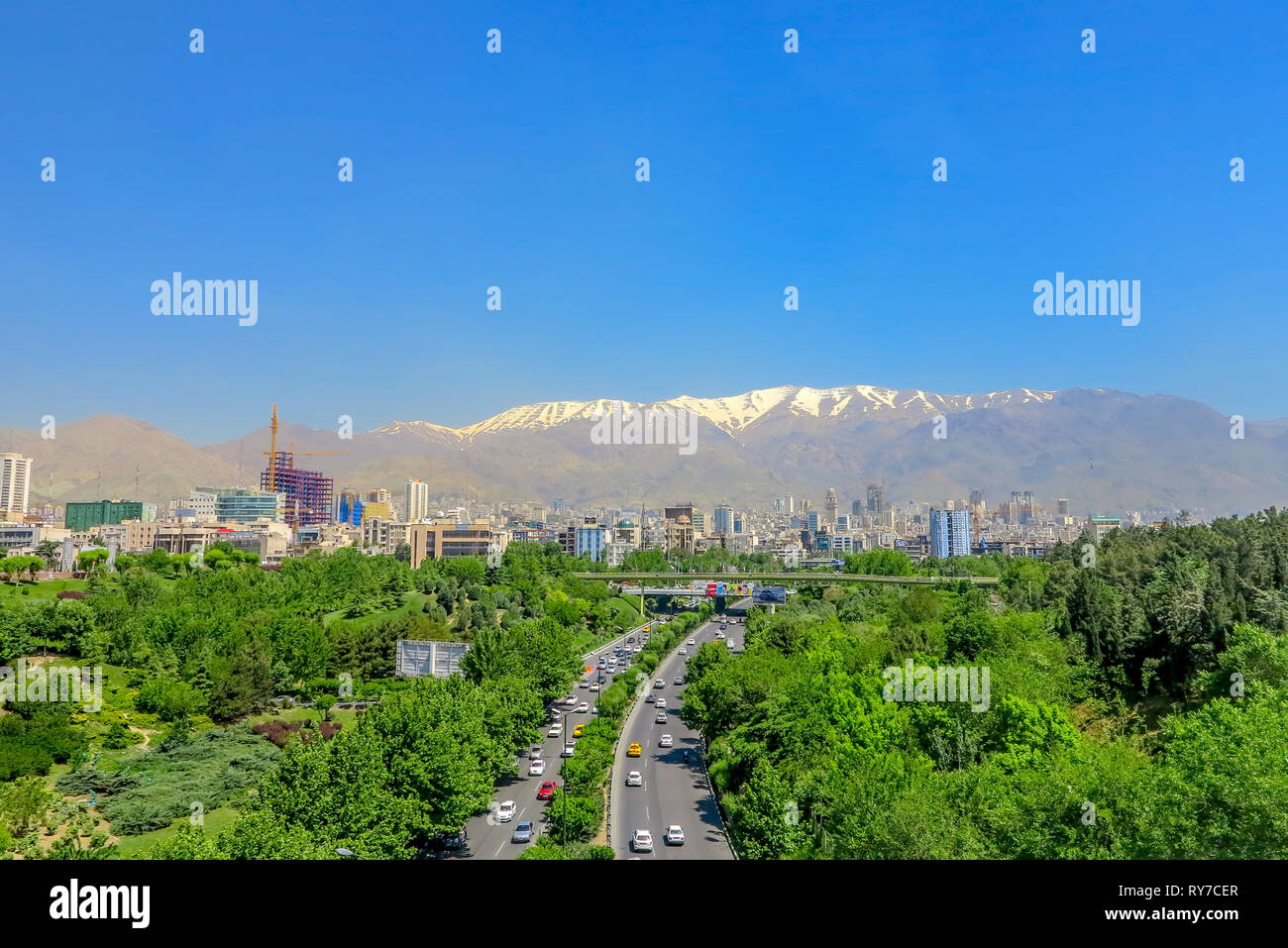 Tehran ab-o Atash parco con vista di Snow capped Mount Tochal Alborz e ad alto traffico Autostrada Foto Stock