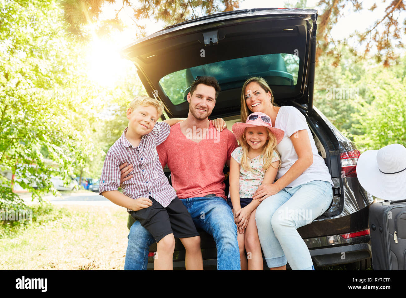 La famiglia felice con bambini è seduto in auto in estate Foto Stock