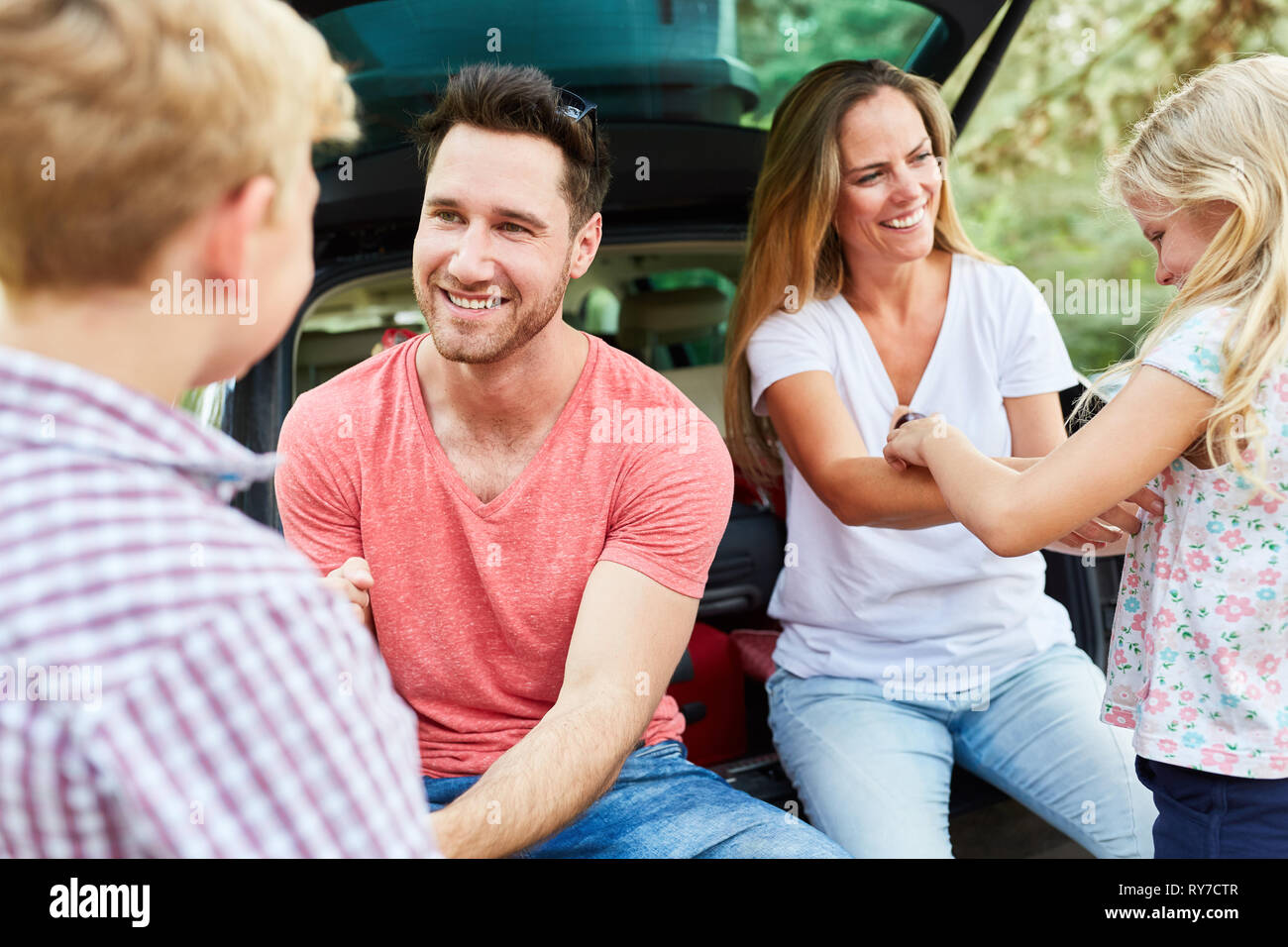 Genitori felici in auto per un viaggio in vacanza con i nostri due bambini Foto Stock