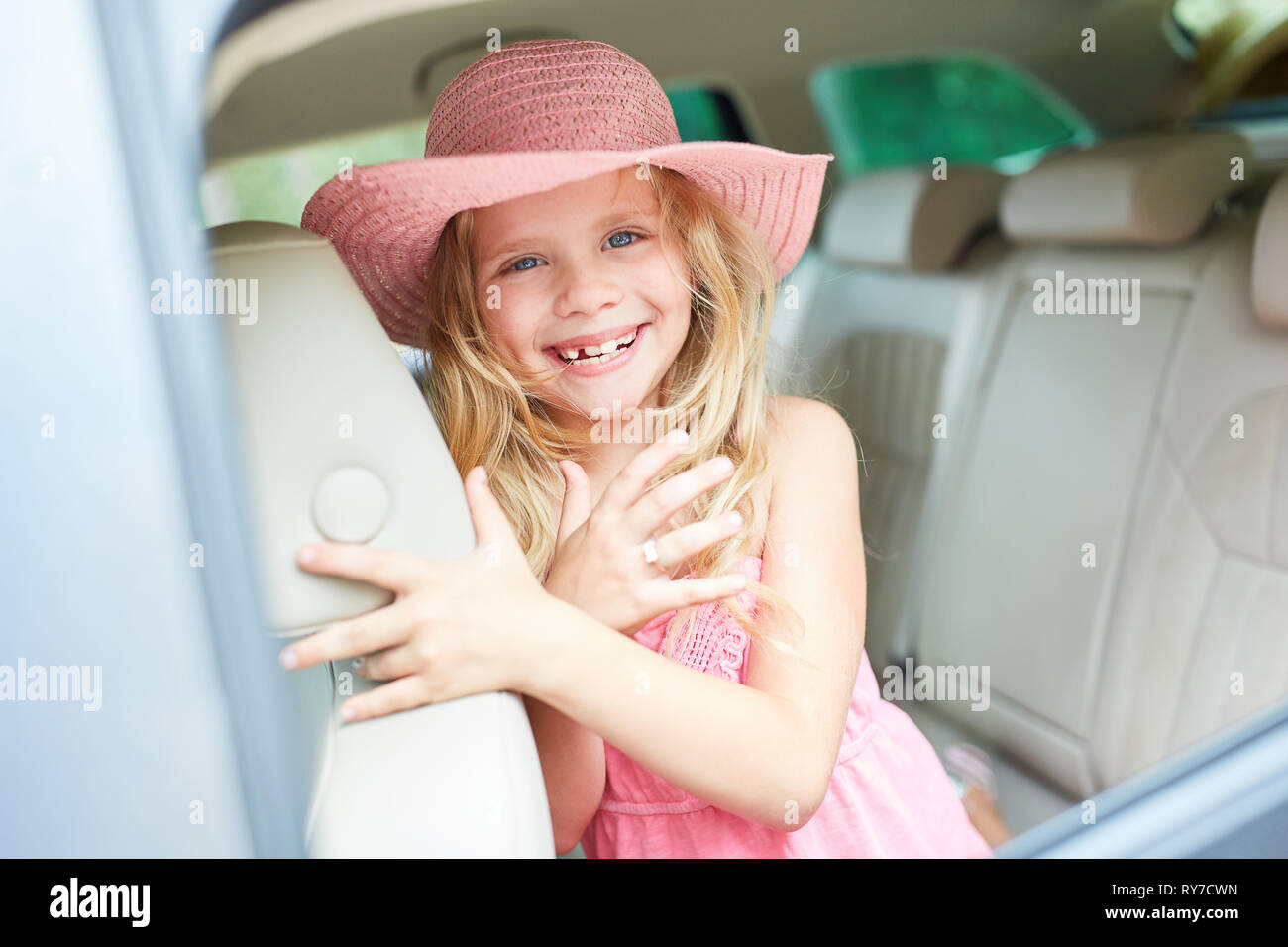 Ragazza con estate hat nel sedile posteriore in auto guardando in avanti per le vacanze estive Foto Stock