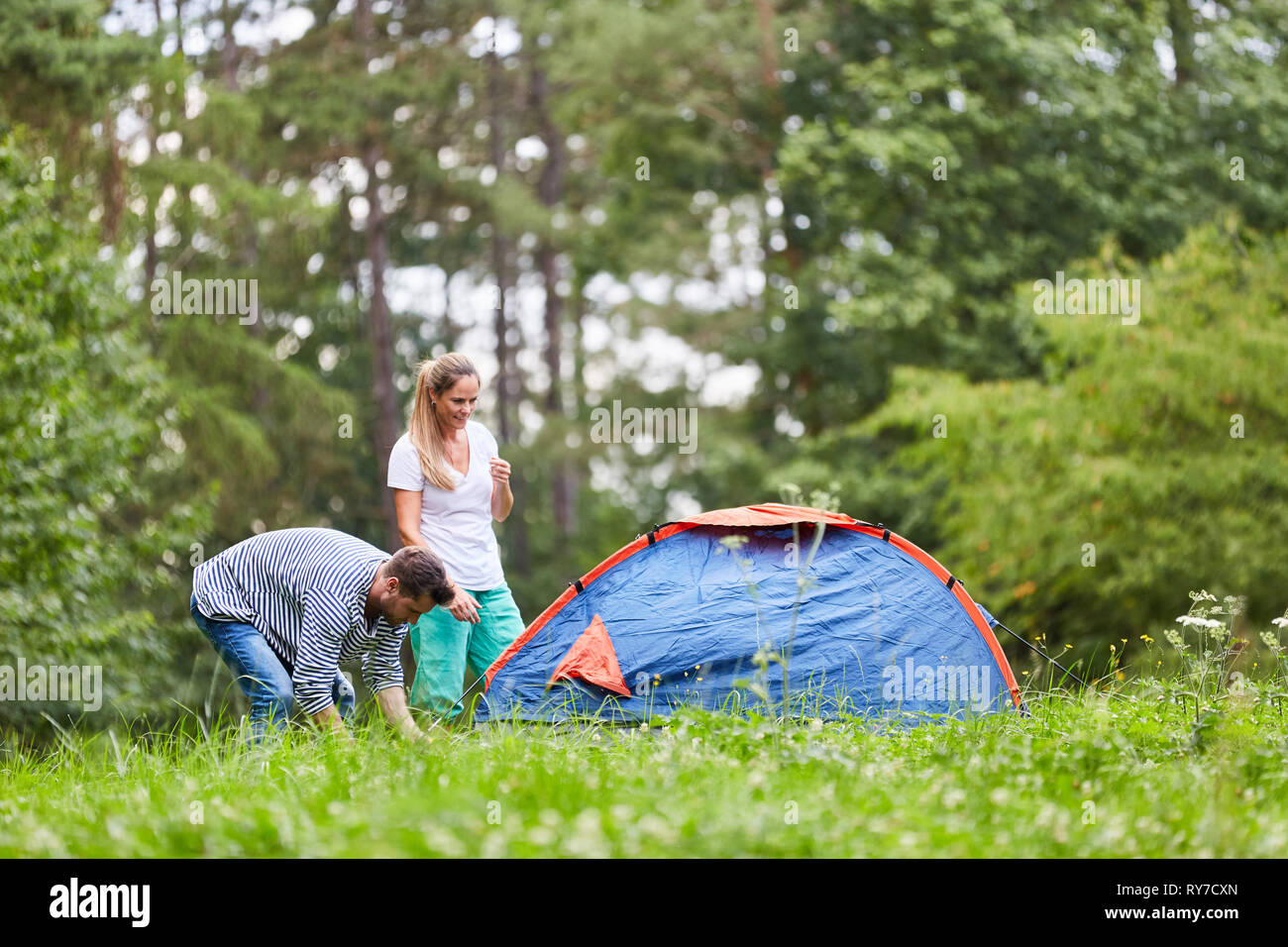Giovane è il campeggio e campeggio su un prato in natura su vacanze estive Foto Stock